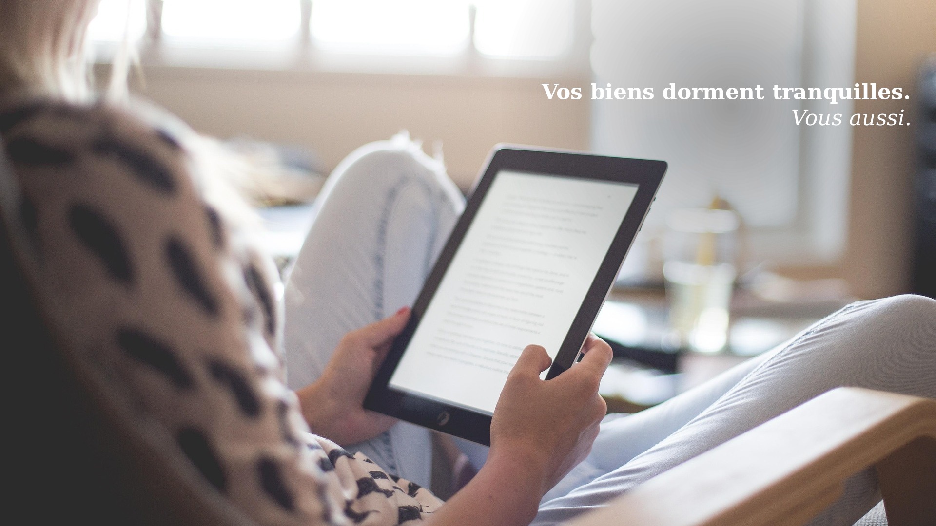 Une personne détendue lit sur une tablette dans un salon lumineux — la sérénité d'un propriétaire dont les biens sont sous contrôle avec Scello.